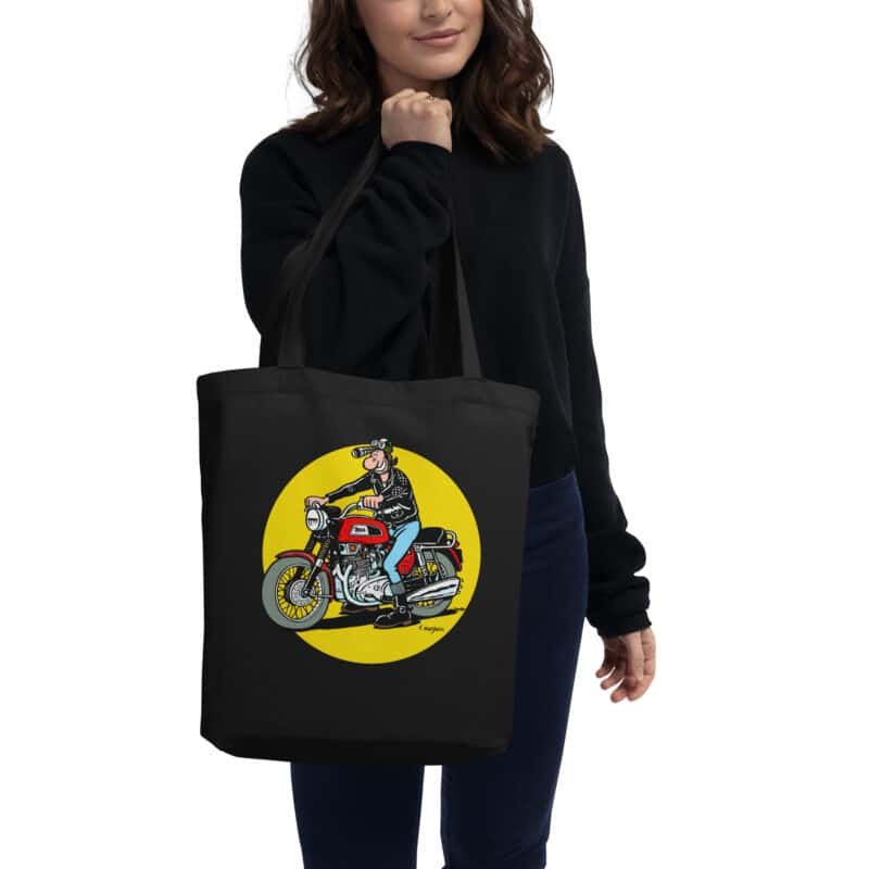 Tote bag noir "Lucien sur moto BSA Trident", illustration rétro et iconique de Frank Margerin, porté à la main.