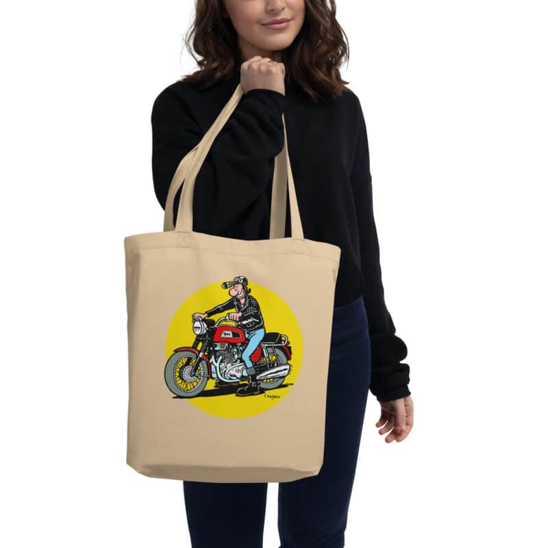 Tote bag beige "Lucien sur moto BSA Trident", illustration rétro et iconique de Frank Margerin, porté à la main.